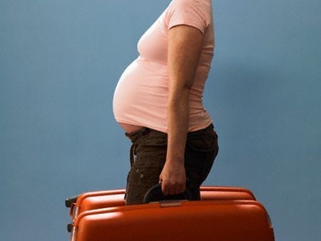 donna incinta con valigie